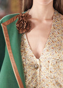 Close-up of a person wearing a green coat with a floral brooch and a patterned top.
