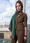Woman in a brown suit standing on a balcony with a cityscape view
